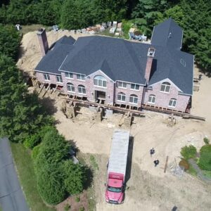 Aerial view of a house lifted at the foundation by building movers - Payne Construction Services
