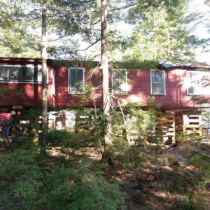 A red house in the woods raised with support beams - Payne Construction Services
