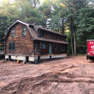 An old cabin-style house in the woods lifted at the foundation - Payne Construction Services