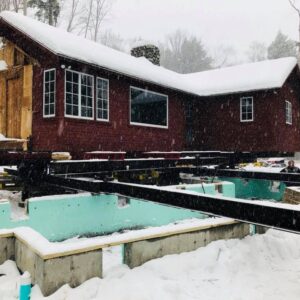 A snow-covered cabin is lifted up from the foundation.