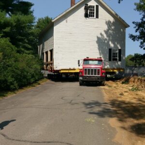 A historical house is taken on a truck down a road.