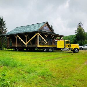 A large cabin with a green roof is built up on the bed of a truck.