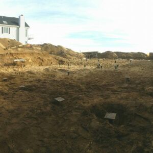 An open dirt lot with helical piles in the ground - Payne Construction Services