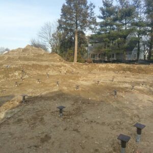 An open lot with helical piles ready for a house - Payne Construction Services