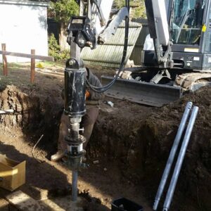 Construction work screwing in helical piles - Payne Construction Services