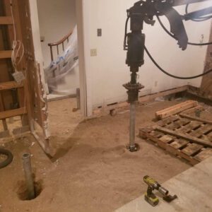 A home's floor dug out and helical piles being installed - Payne Construction Services