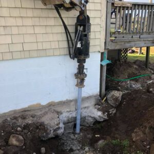 Helical piles being installed near home's foundation - Payne Construction Services