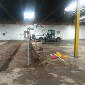 Digging channels in a commercial building for helical pile project - Payne Construction Services