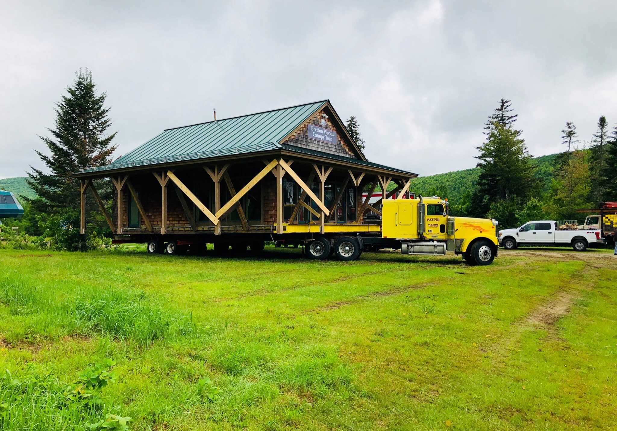 A large cabin with a green roof is built up on the bed of a truck.